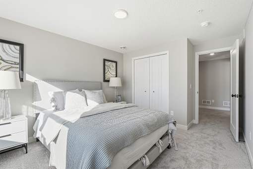 A bedroom with a bed, nightstand, and a painting on the wall.