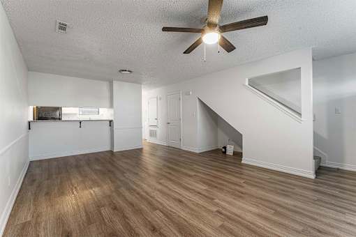 A room with a ceiling fan and wooden flooring.