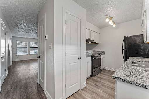 A kitchen with a black fridge and a granite counter top.