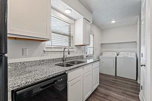 A kitchen with a granite countertop and white cabinets.