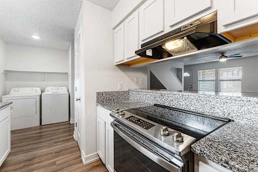 A kitchen with a stove top oven and white cabinets.
