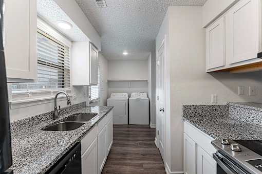 A kitchen with granite countertops and white cabinets.