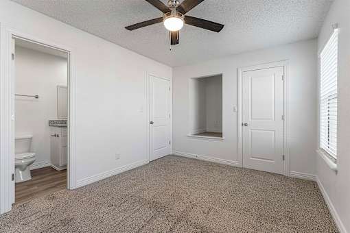 A room with a ceiling fan and carpeted floor.