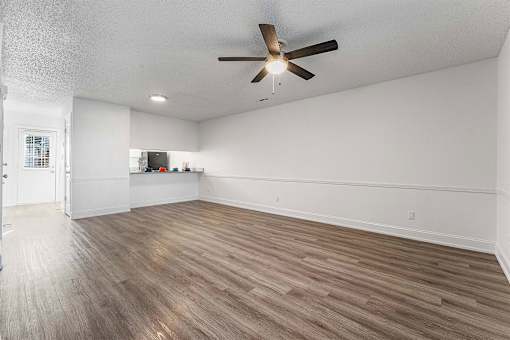 A room with a ceiling fan and wooden flooring.