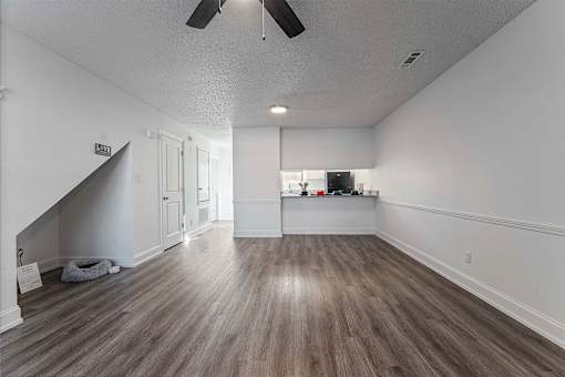 A room with a staircase on the left and a kitchenette on the right.