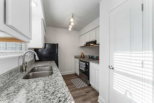 A kitchen with a black refrigerator and a marble countertop.