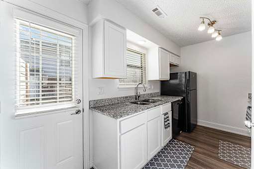 A kitchen with white cabinets and a black refrigerator.