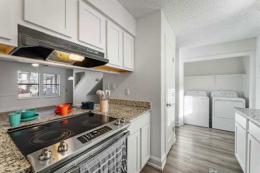 A kitchen with a black stove top oven and white cabinets.