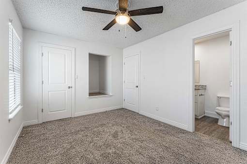 A room with a ceiling fan and carpeted floor.