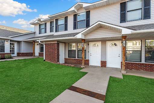 A house with a white door and windows with a green lawn in front.