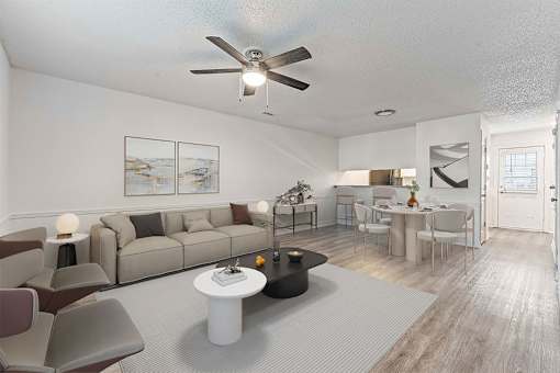 A living room with a grey couch, a white coffee table, and a ceiling fan.