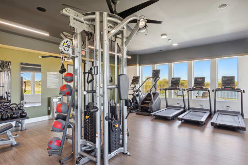 a gym with weights and cardio equipment and windows
