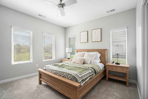 A bedroom with a bed, nightstand, and window blinds.