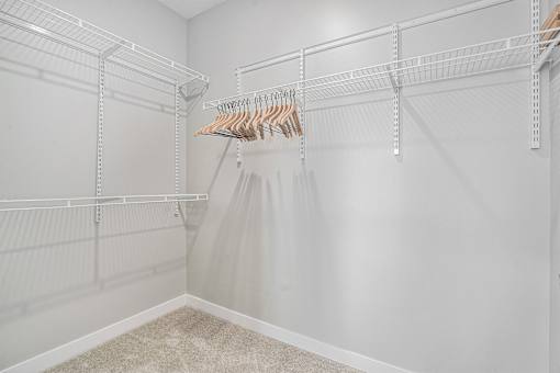 A white closet with a hanging dress and a carpet on the floor.