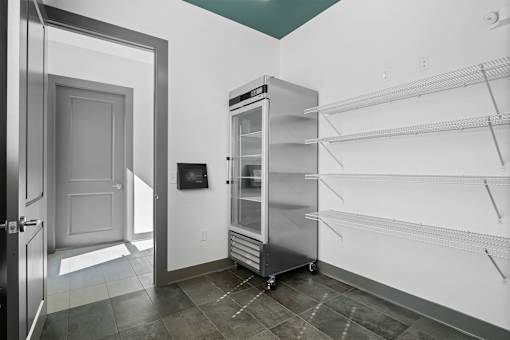 A kitchen with a refrigerator and empty shelves.