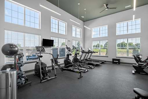 A spacious gym with a variety of exercise equipment and large windows.