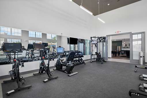 A gym with a variety of exercise equipment including treadmills, stationary bikes, and weight machines.