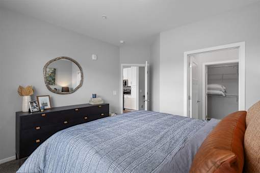 A bedroom with a blue bedspread and a brown leather couch.