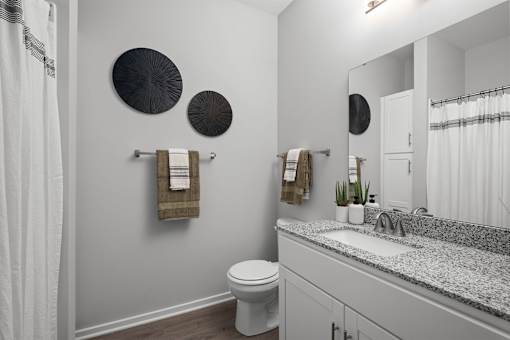 A bathroom with a toilet, sink, mirror, and towel rack.