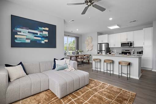 A modern living room with a grey sofa and a painting on the wall.
