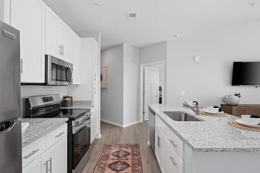 A kitchen with white cabinets and a black fridge.