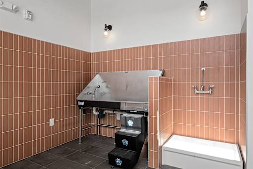 A bathroom with a brown tiled wall and a white bathtub.