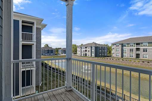 A balcony with a railing overlooking a body of water with buildings in the background.