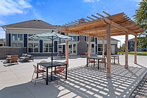 A patio with a table and chairs under a wooden pergola.