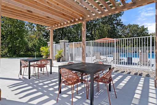 A patio with a table and chairs under a wooden pergola.