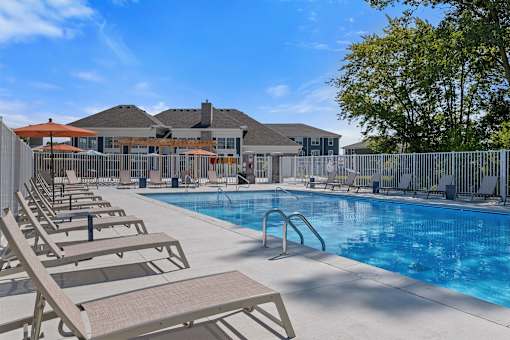 A pool with sun loungers and a building in the background.