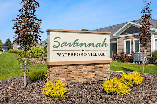 A sign for Savannah Waterford Village is displayed in front of a house.