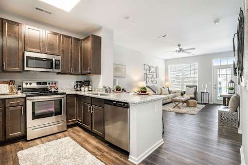 A modern kitchen with dark wood cabinets and stainless steel appliances.