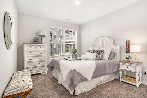 A bedroom with a bed, nightstand, and chair.