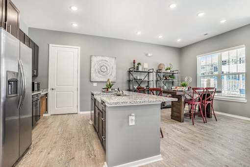 A kitchen with a refrigerator, island, and dining table.