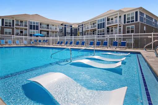 A large swimming pool with a white diving board in front of a building.