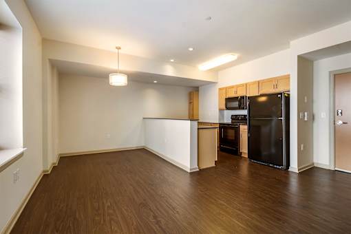 A kitchen with a black fridge and wooden cabinets.