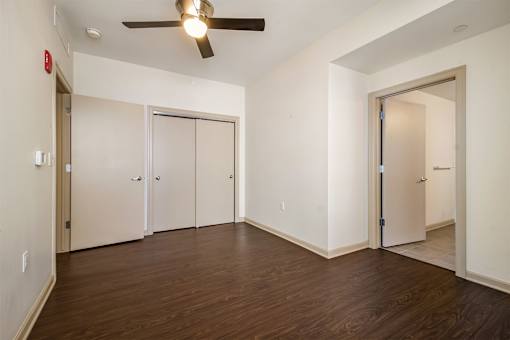 A room with a ceiling fan and wooden floors.