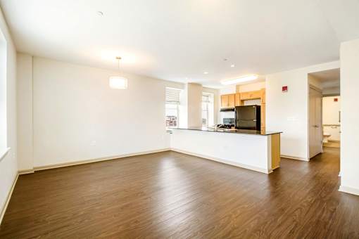 A spacious kitchen with a wooden floor and white walls.