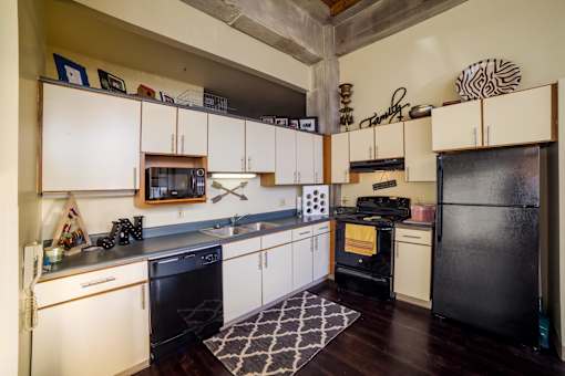 A kitchen with black appliances and white cabinets.