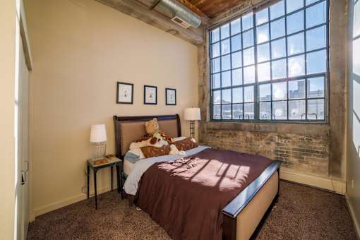 A bedroom with a large bed and a teddy bear on it.