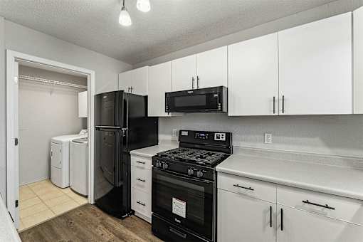 A kitchen with black appliances and white cabinets.