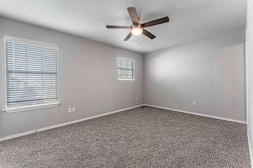 A room with a ceiling fan and carpeted floor.