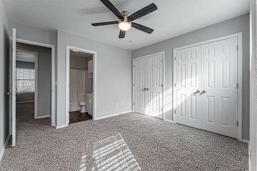 A room with a ceiling fan and three doors.