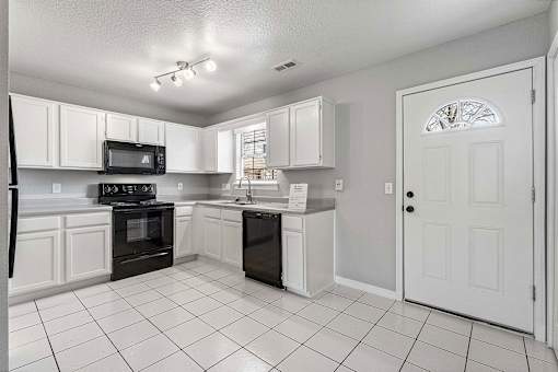 A kitchen with white cabinets and black appliances.