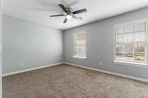 A room with a ceiling fan and carpeted floor.
