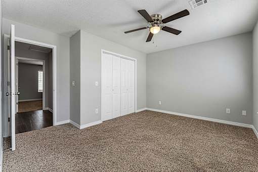 A room with a ceiling fan and carpeted floor.