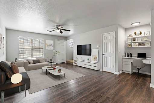 A living room with a couch, a coffee table, a television, and a desk.
