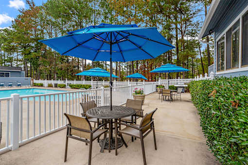 A blue umbrella is over a table with chairs.