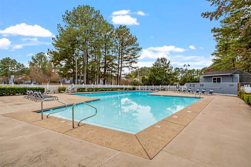A swimming pool surrounded by trees and a small building.