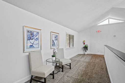 A room with two chairs and two framed pictures on the wall.